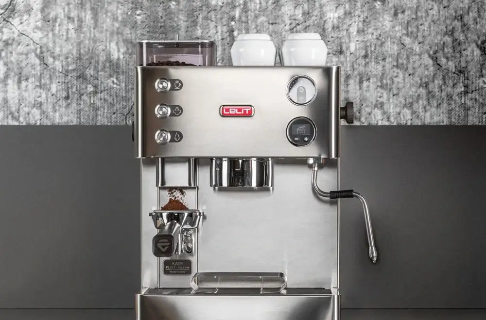 Front view of the Lelit Kate combi espresso machine with built-in grinder, placed on a wooden console table in a modern home setting with a plant and books.