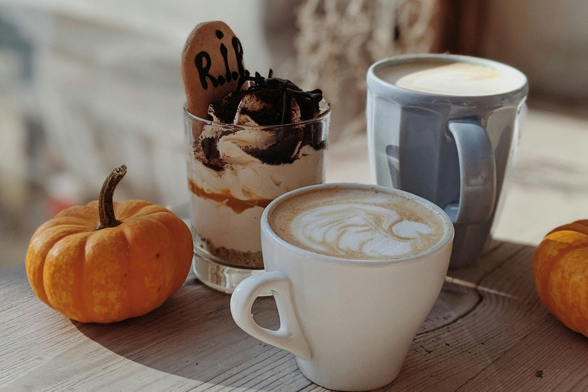 3 coffees and a pumpkin sat on a table.