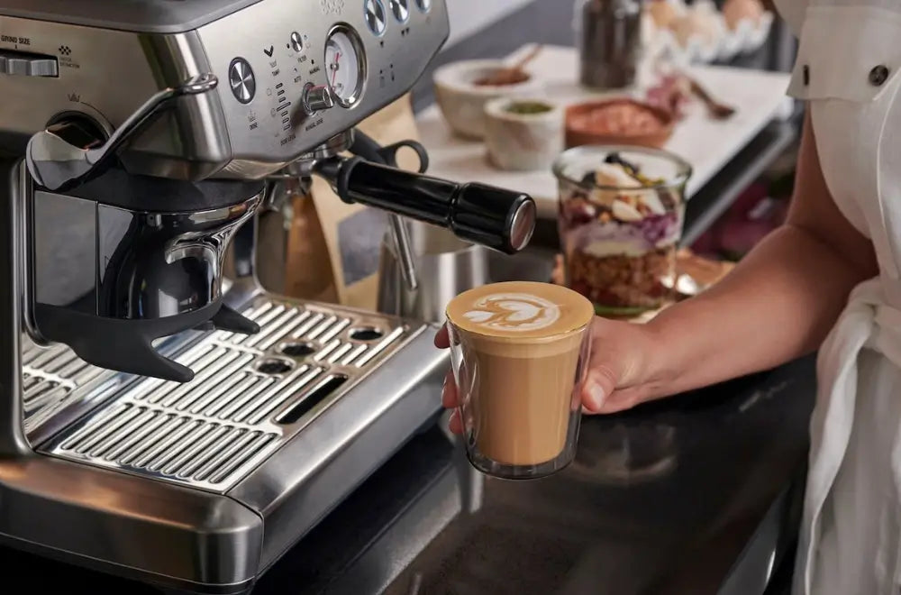 Action shot of a barista texturing milk in a stainless steel jug using the steam wand of a Sage Barista Pro.
