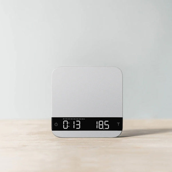 Grey Acaia Lunar espresso scale showing digital timer and weight readout in a modern minimalist style.