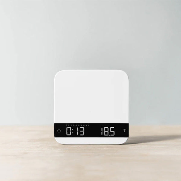 White Acaia Lunar espresso scale showing digital timer and weight readout in a modern minimalist style.