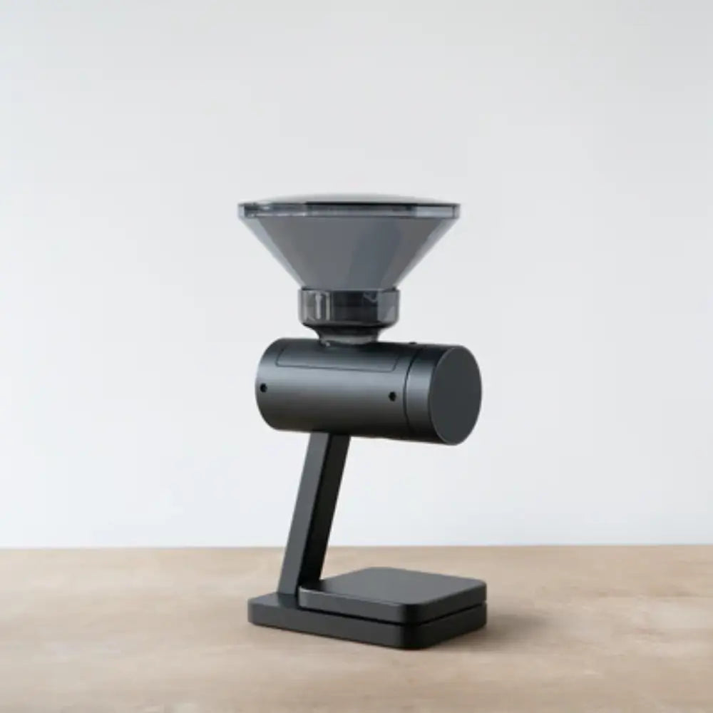 Side view of the Acaia Orion Nano coffee bean doser in black with a transparent hopper on a wooden surface.