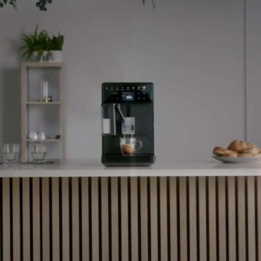 Bestir Melange coffee machine on office counter brewing coffee into glass.