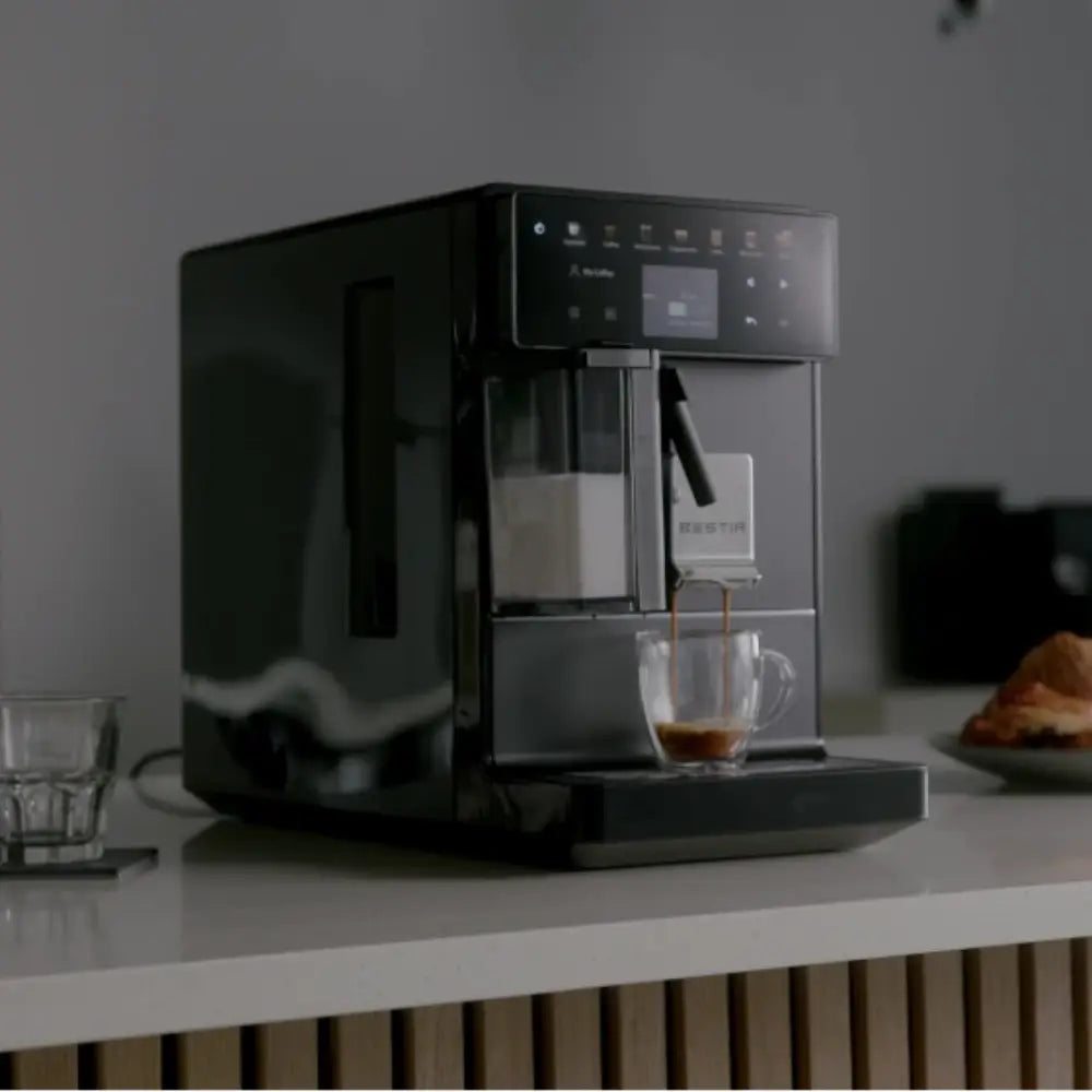Bestir Melange coffee machine on office counter brewing espresso into glass cup.