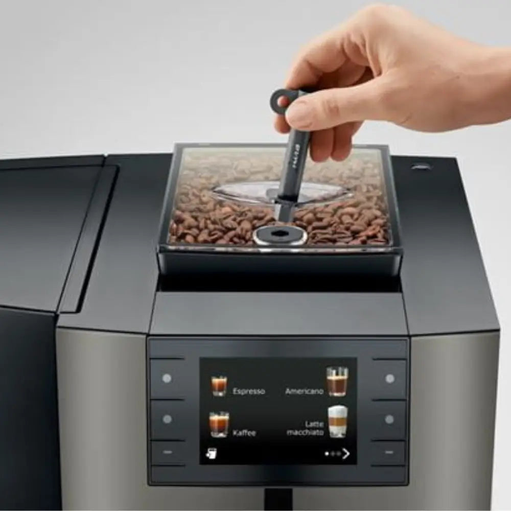 Jura X10c coffee machine with hand refilling coffee beans into the hopper.