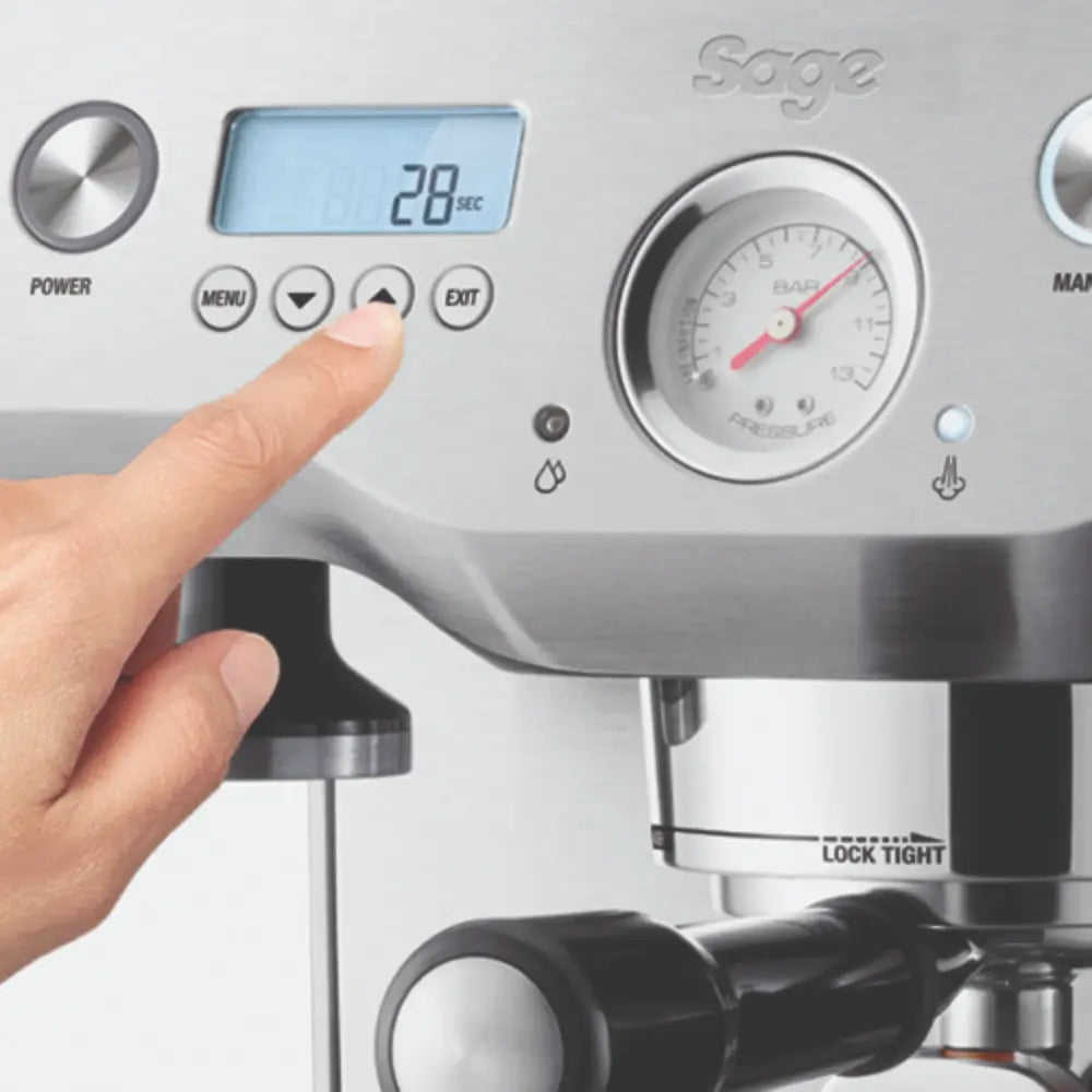Close-up of a finger pressing a menu button on the Sage Dual Boiler's LCD display, showing the digital shot timer.