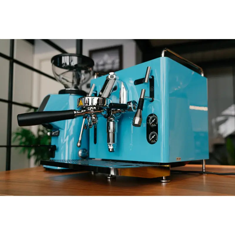 Lifestyle shot of the yellow Sanremo Cube R espresso machine paired with a matching commercial grinder on a wooden bar.