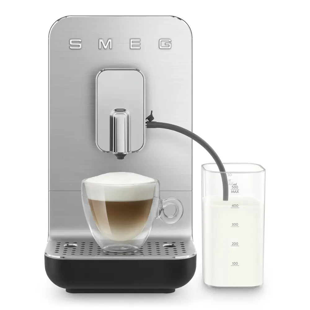 The SMEG BCC13 actively frothing milk and pouring a cappuccino into a glass mug via the integrated system.