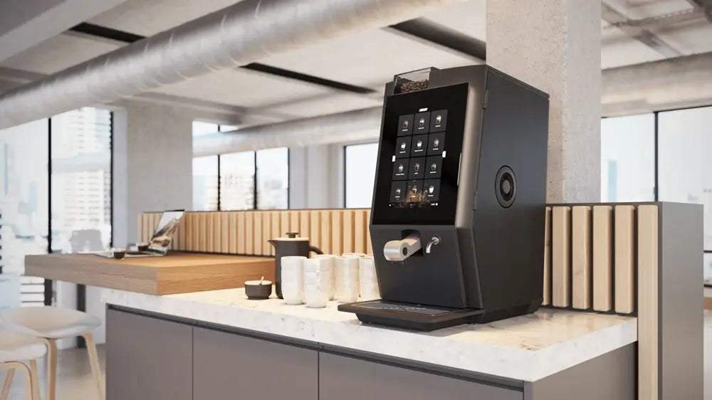 Bravilor Esprecious commercial automatic coffee machine on a marble counter in a modern industrial office breakroom.