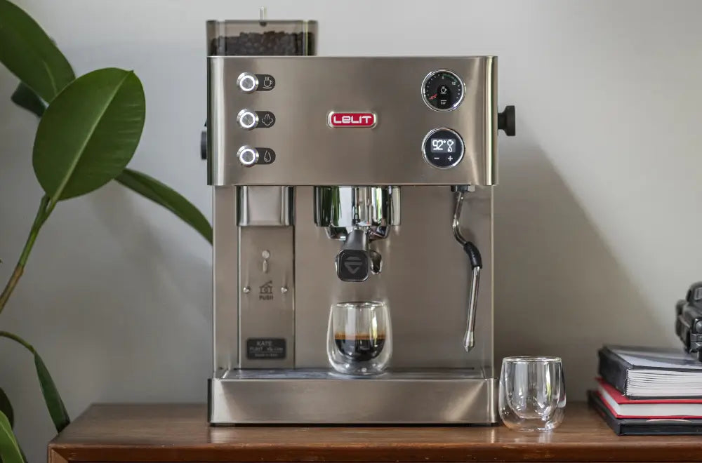 Front view of the Lelit Kate combi espresso machine with built-in grinder, placed on a wooden console table in a modern home setting with a plant and books.