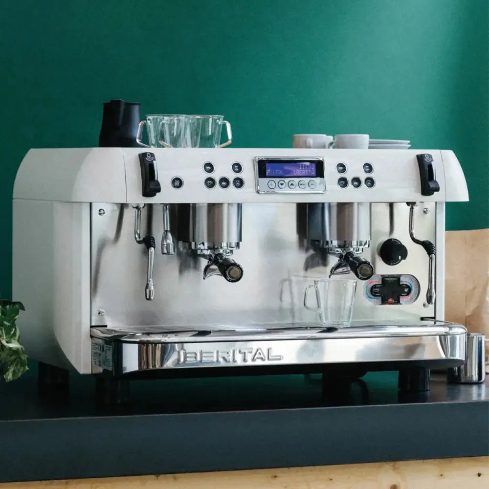 White Iberital New PID 2 Group espresso machine on a cafe counter with a green background, showing cup clearance.