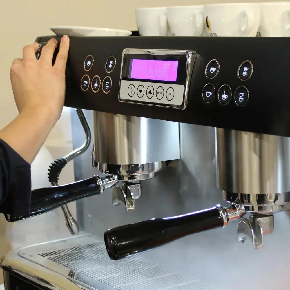 Close-up of a barista's hand adjusting the control panel and programmable dose buttons on the New Iberital PID espresso machine.