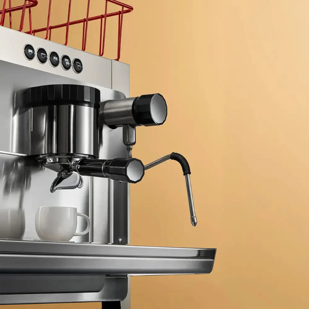 Close-up detail of the Iberital Tandem group head, portafilter, and adjustable steam wand with a white cup waiting.