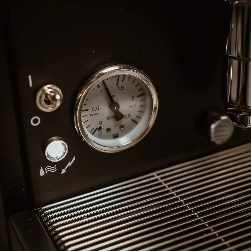 Close-up of the boiler pressure gauge and power switch on the black Cellini Classic.
