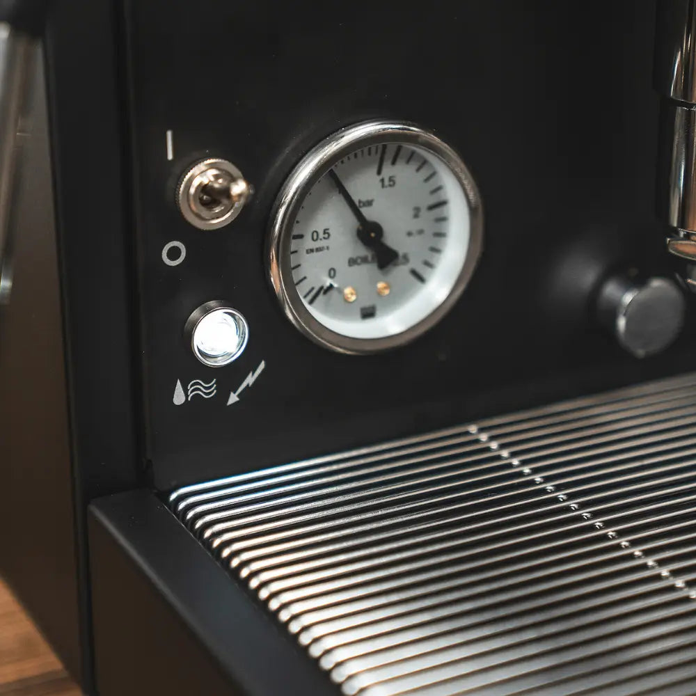 Close-up of the boiler pressure gauge and indicator lights on the black Cellini Evolution.