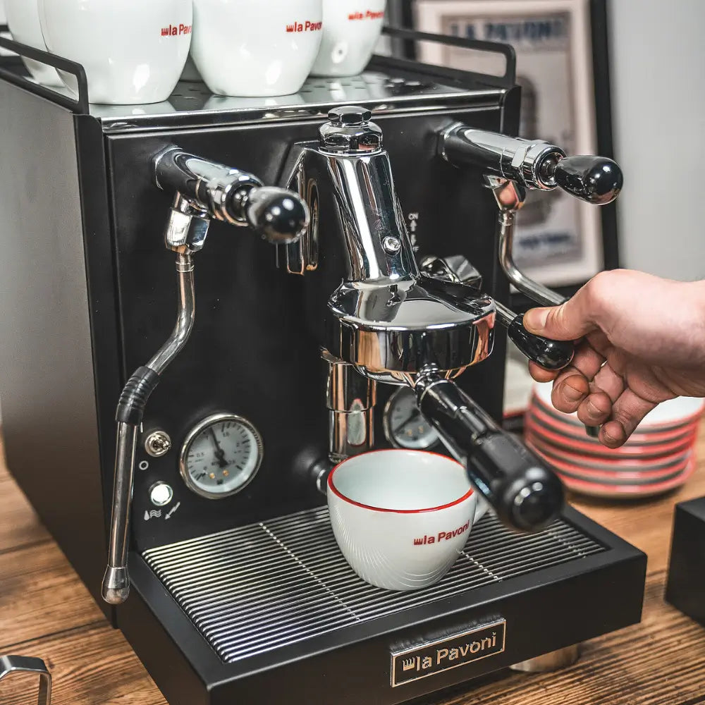 A hand pulling the brew lever to start an espresso shot on the La Pavoni Cellini Evolution.