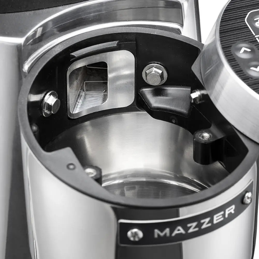 Close-up of the open grinding chamber on a Mazzer Kold S, showing the swing-open electronic display and access to the anti-clumping chute for easy cleaning.