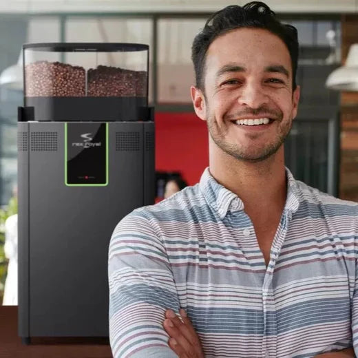 Smiling man standing beside the Rex-Royal S300 bean-to-cup espresso coffee machine in a stylish modern indoor setting
