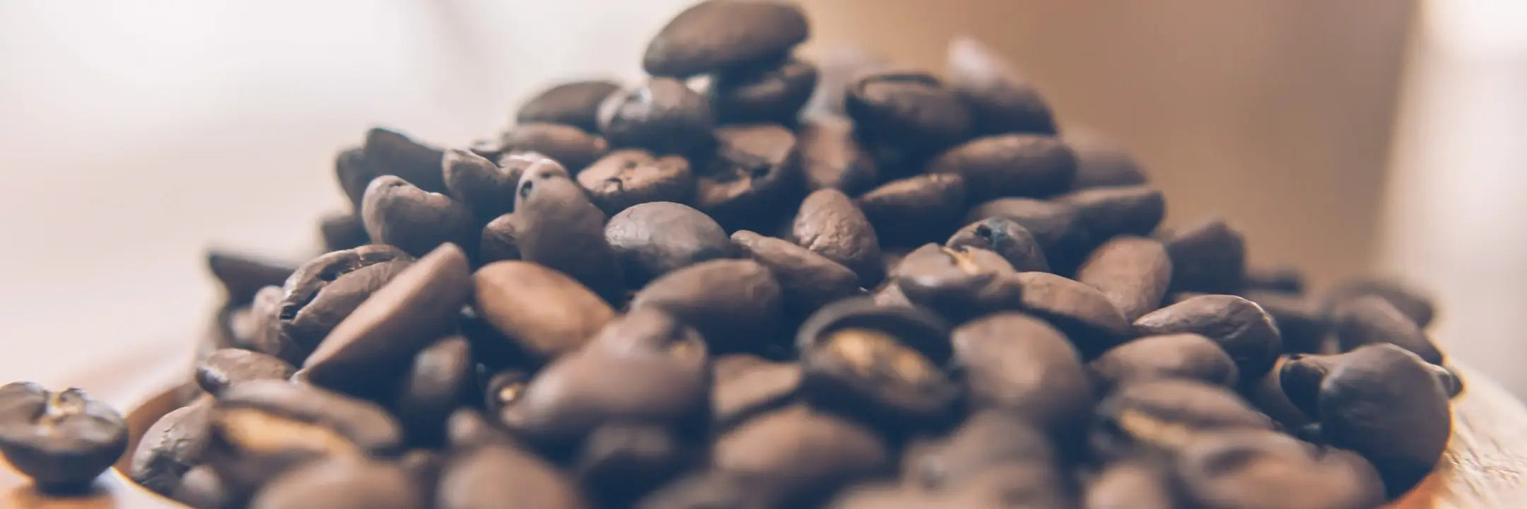 Close-up of roasted coffee beans on a wooden surface with a blurred background