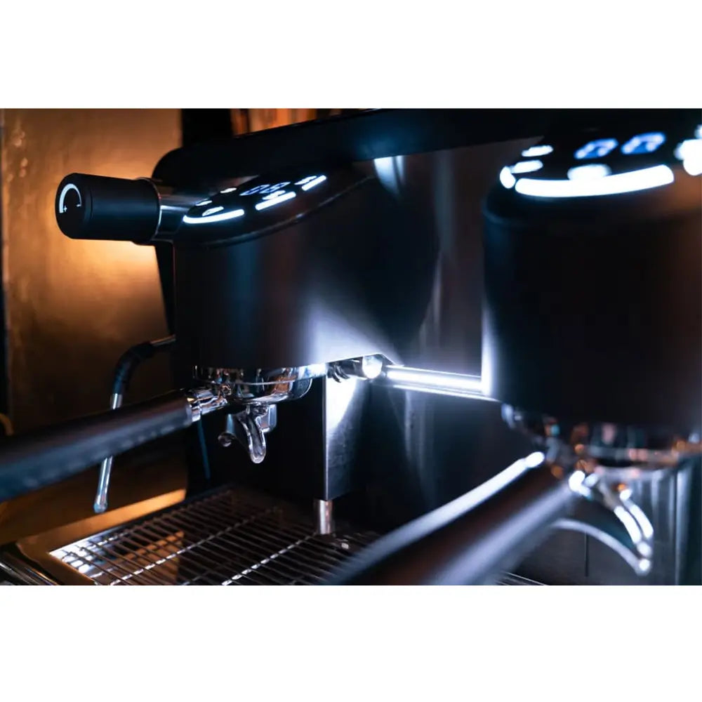 Close-up of the F18's two digital group heads, showing the chrome plating and illuminated controls.