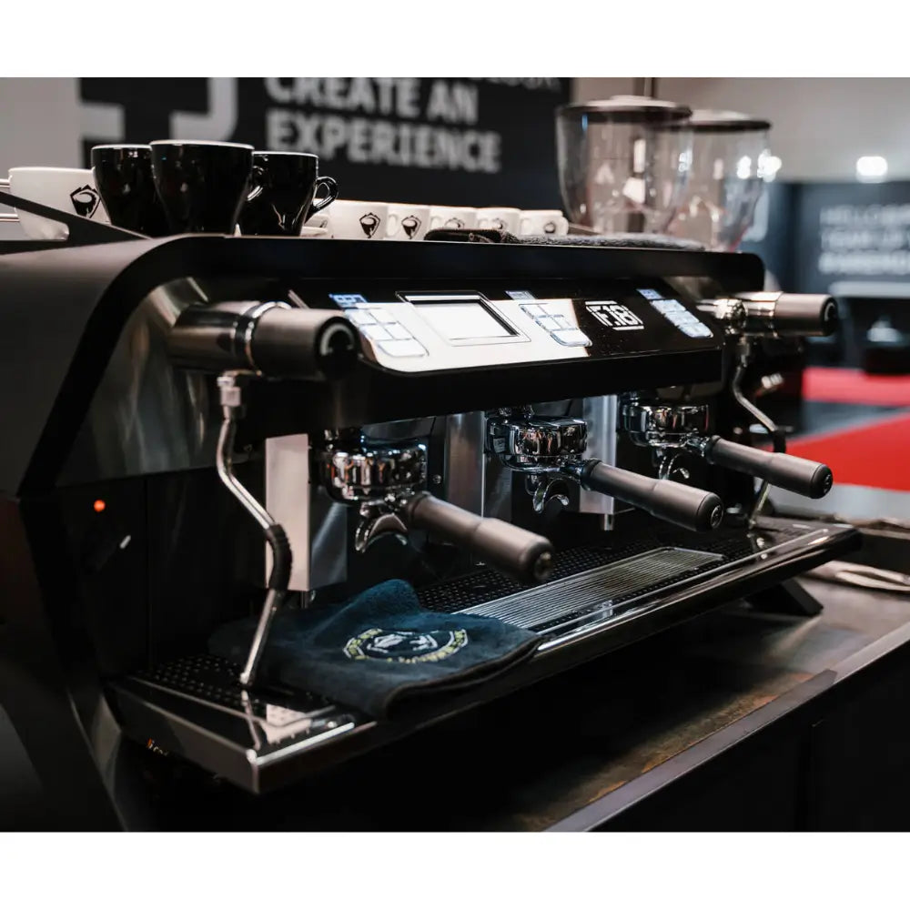 Side view of the Sanremo F18 Multi Boiler on a commercial coffee bar, demonstrating its sleek profile and cup-warming rail.