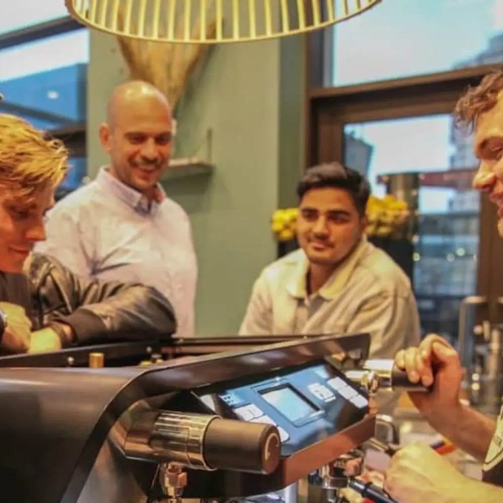 Lifestyle shot of a barista preparing coffee on the Sanremo F18 Multi Boiler while interacting with customers.