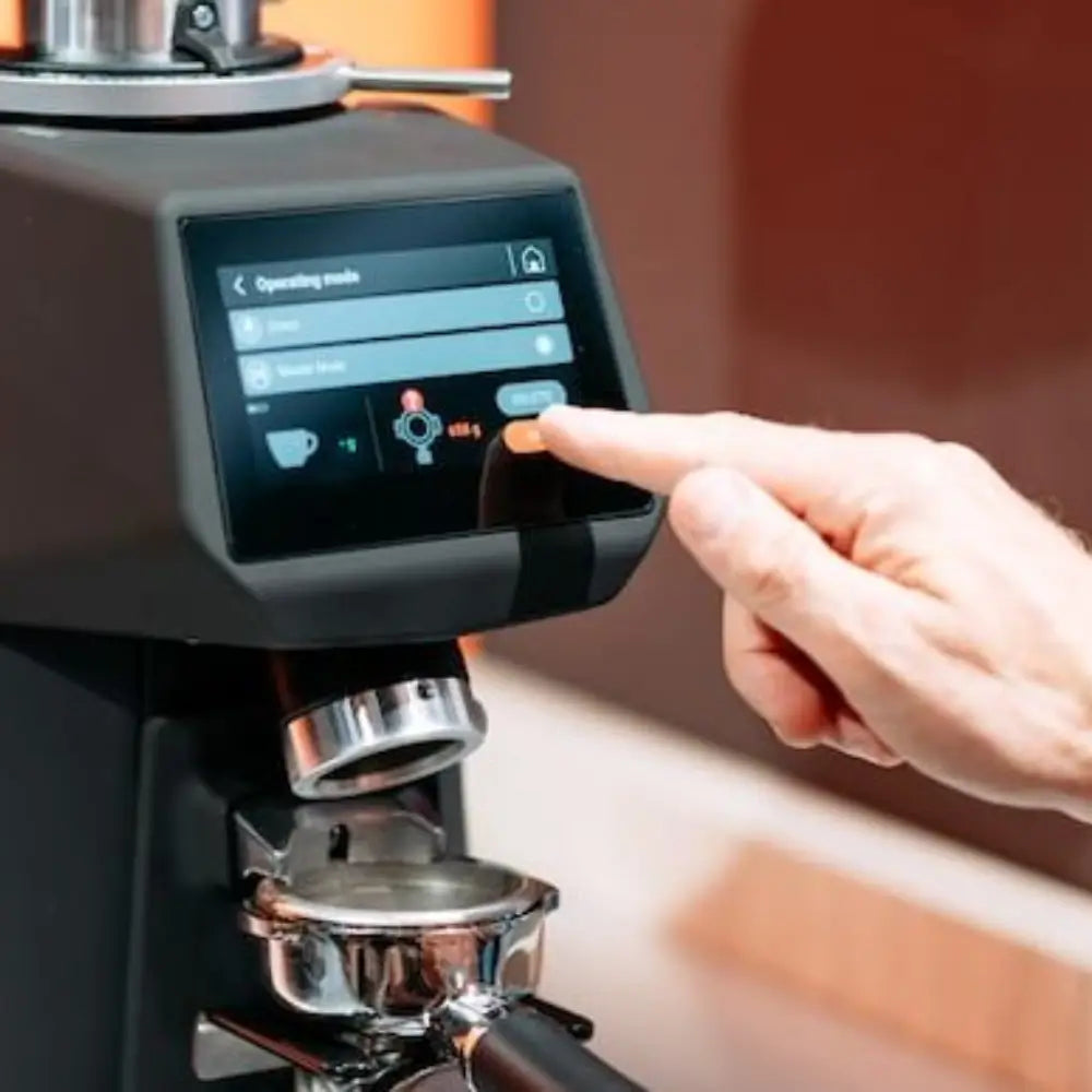 A hand interacting with the digital touchscreen menu on the Sanremo SR64 EVO Pro Sense, selecting the grind-by-weight operating mode.