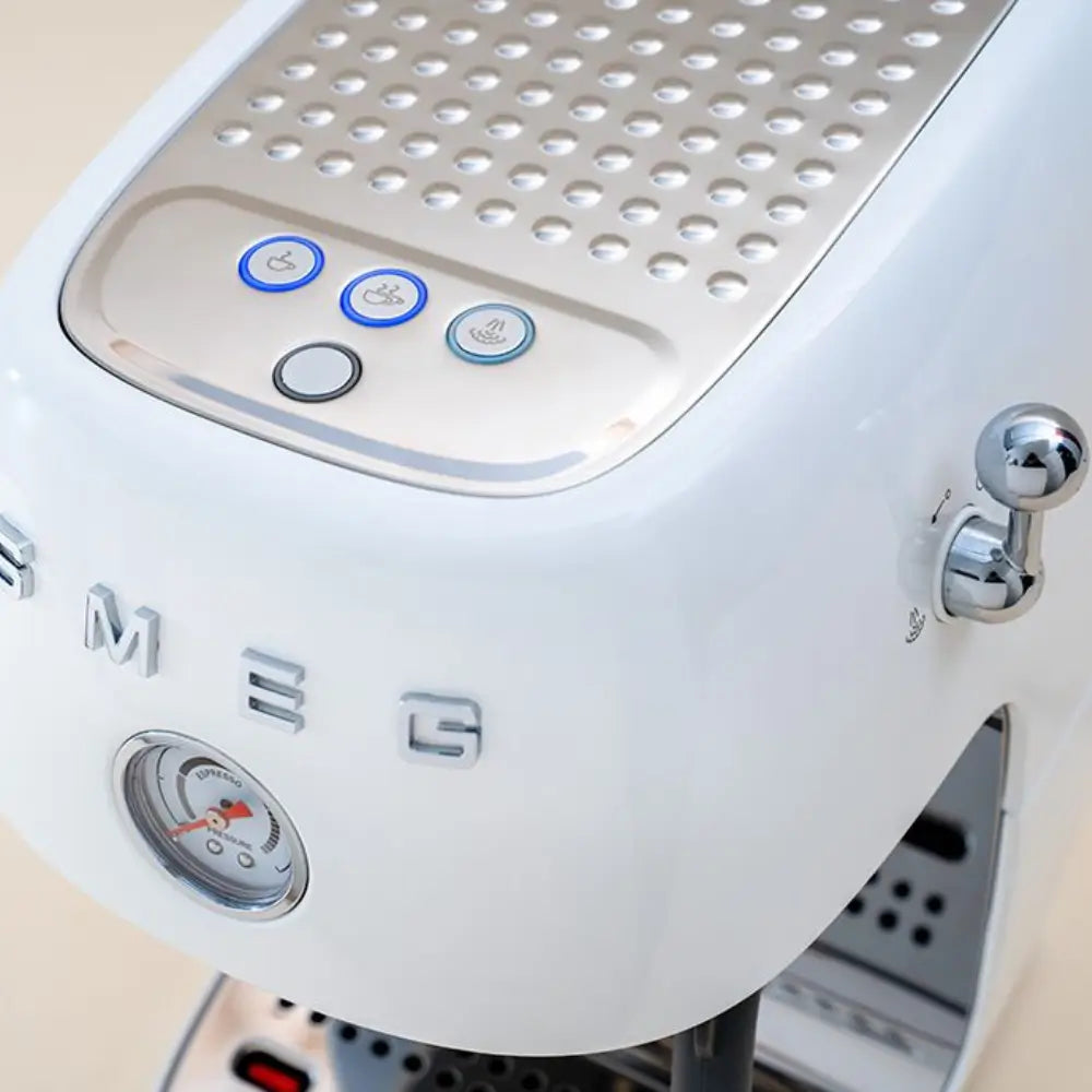 Close-up of the white SMEG ECF03 espresso maker showing the pressure gauge and illuminated coffee function buttons.
