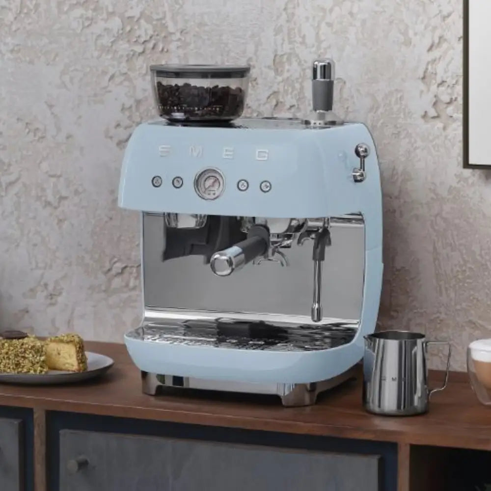 The pastel blue SMEG EGF03 espresso machine displayed on a kitchen counter in a lifestyle setting.