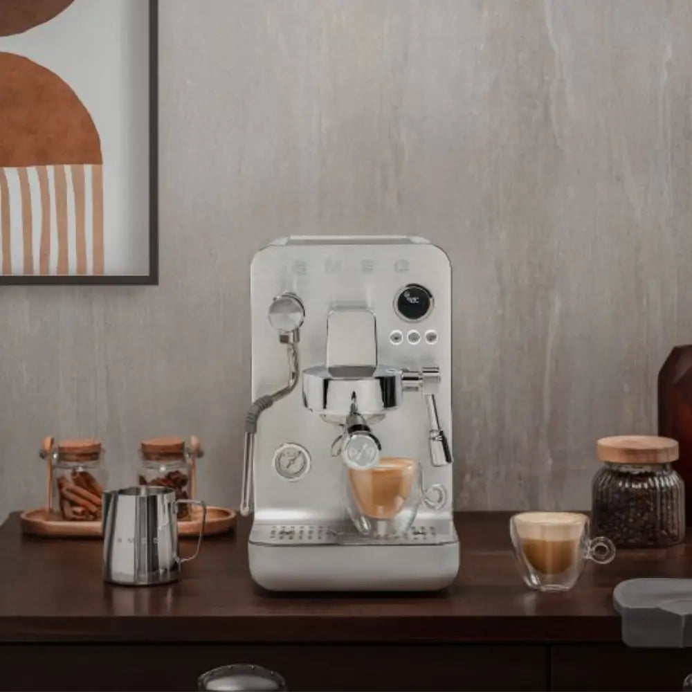 SMEG Collezione Minipro brewing double espresso shots in a modern kitchen with a brick backsplash.