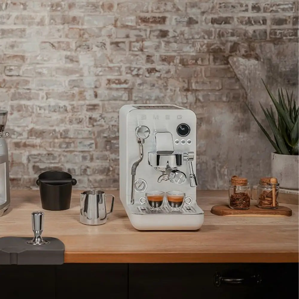 SMEG Minipro semi-automatic espresso machine set up on a stylish wooden counter in a home kitchen.
