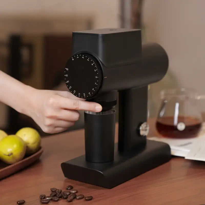 Hand adjusting grind settings on black Timemore Sculptor 064S grinder.
