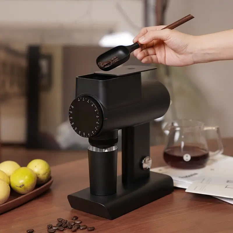 Black Timemore Sculptor 064S coffee grinder with beans being poured into hopper.