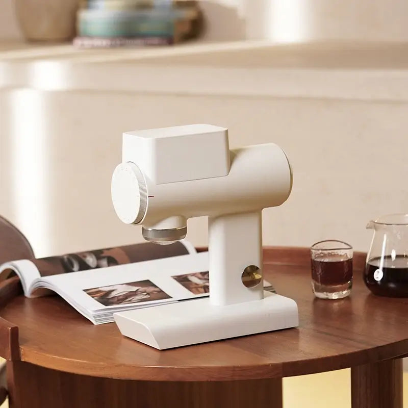 White Timemore Sculptor 064S coffee grinder on wooden table with coffee cups.