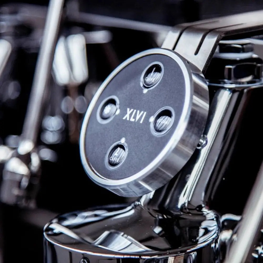 Extreme close-up of the XLVI group head, highlighting the 'XLVI' text and the chrome-ringed volumetric dose buttons.